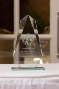 A glass award on a table in front of a window.