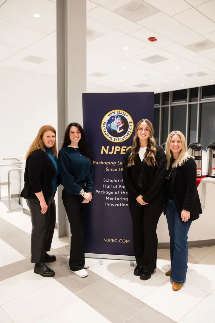 Four women standing beside NJPEC banner.