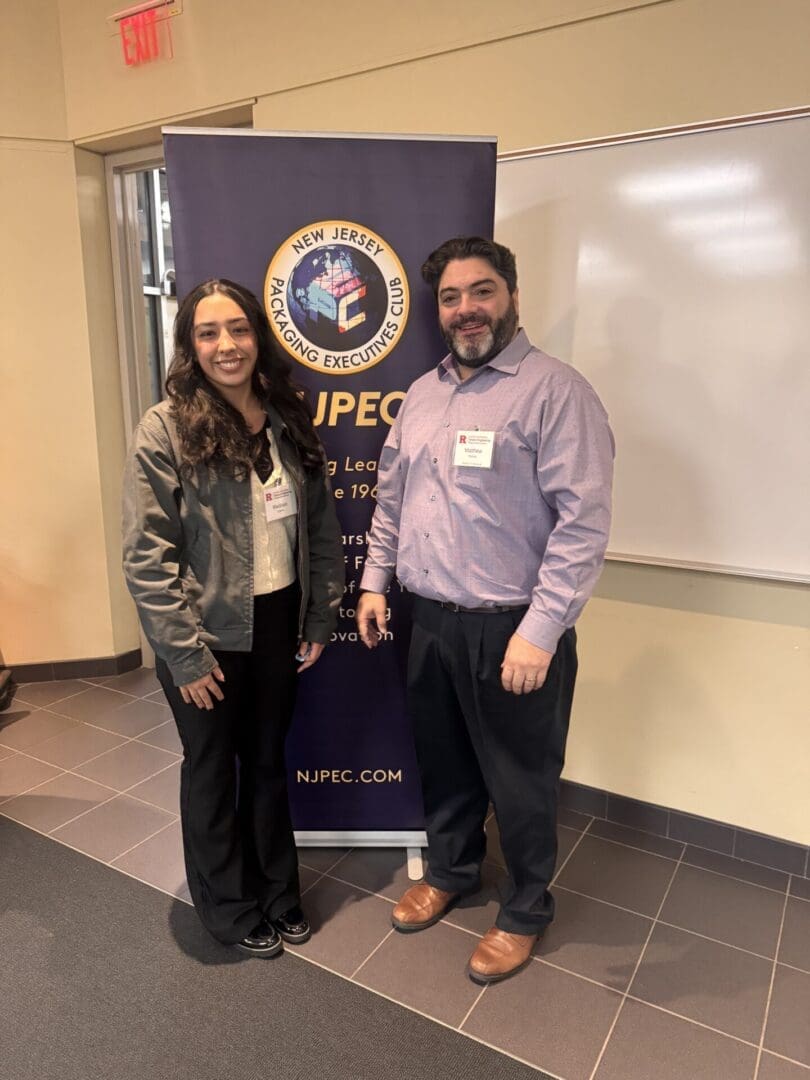 Two people standing beside NJPEC banner.