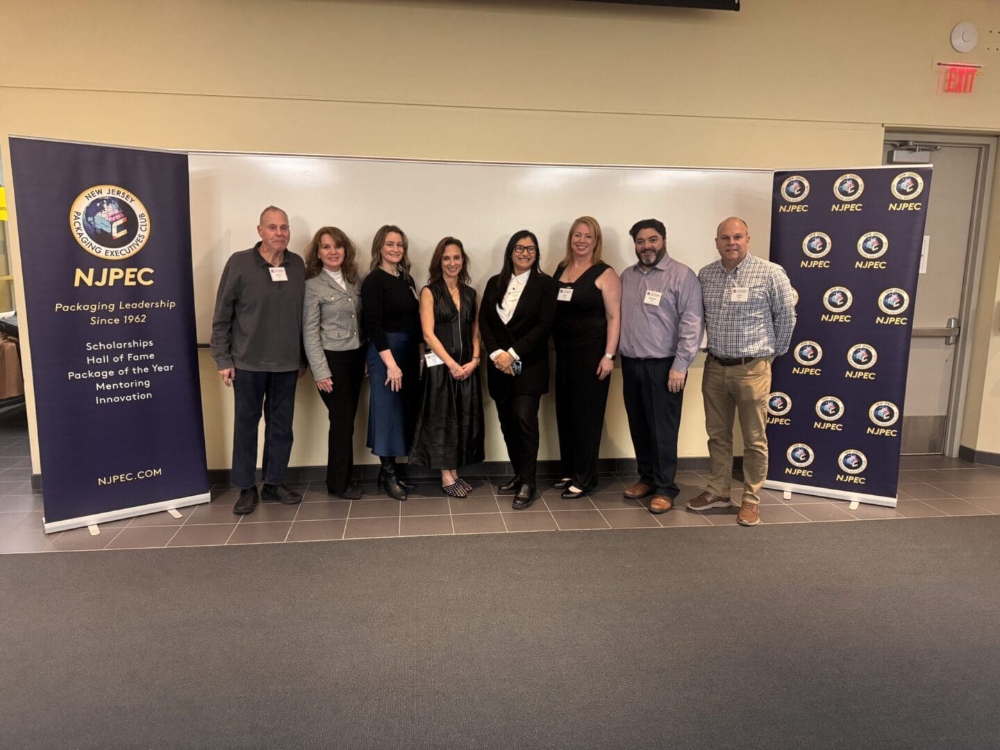 People stand smiling in front of an NJPEC backdrop