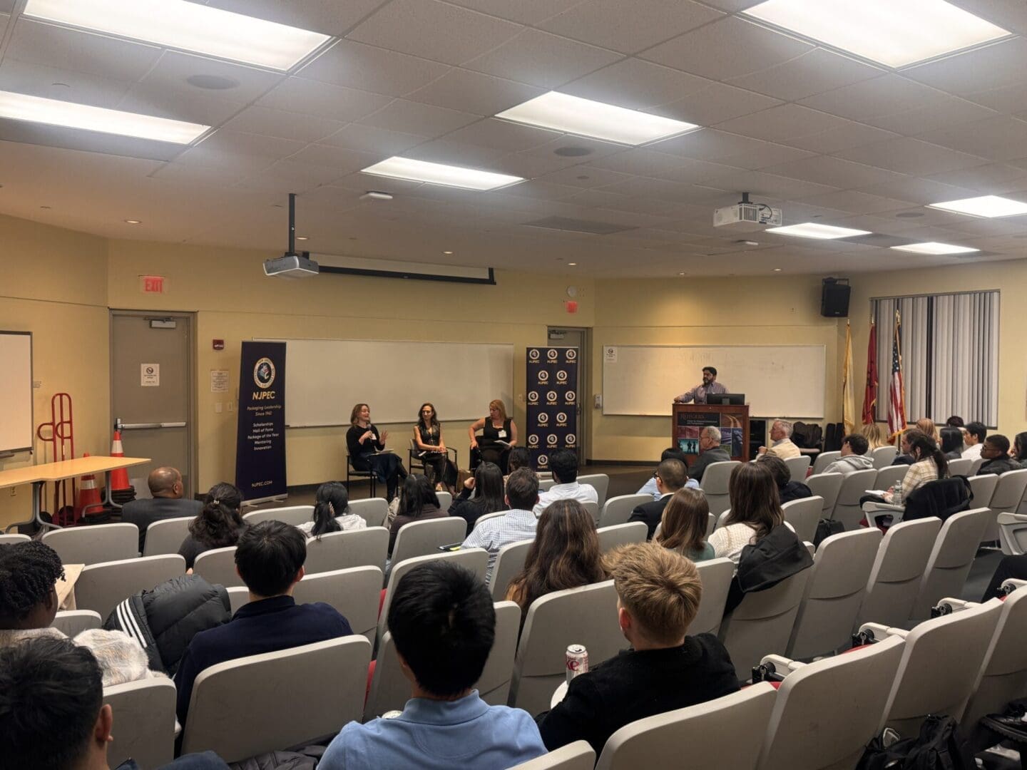 A panel of three people speaks to an audience in a lecture hall