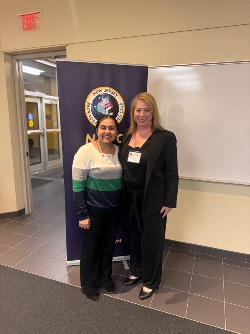 Two people smiling in front of banner.