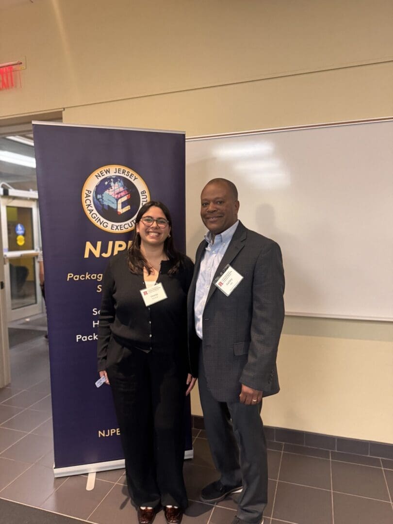 Two people smiling at a conference event.